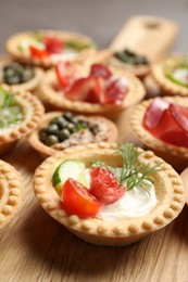 Delicious canapes with dry smoked sausage and cream cheese on table, closeup