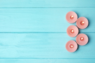 Burning decorative candles on light blue wooden table, flat lay. Space for text