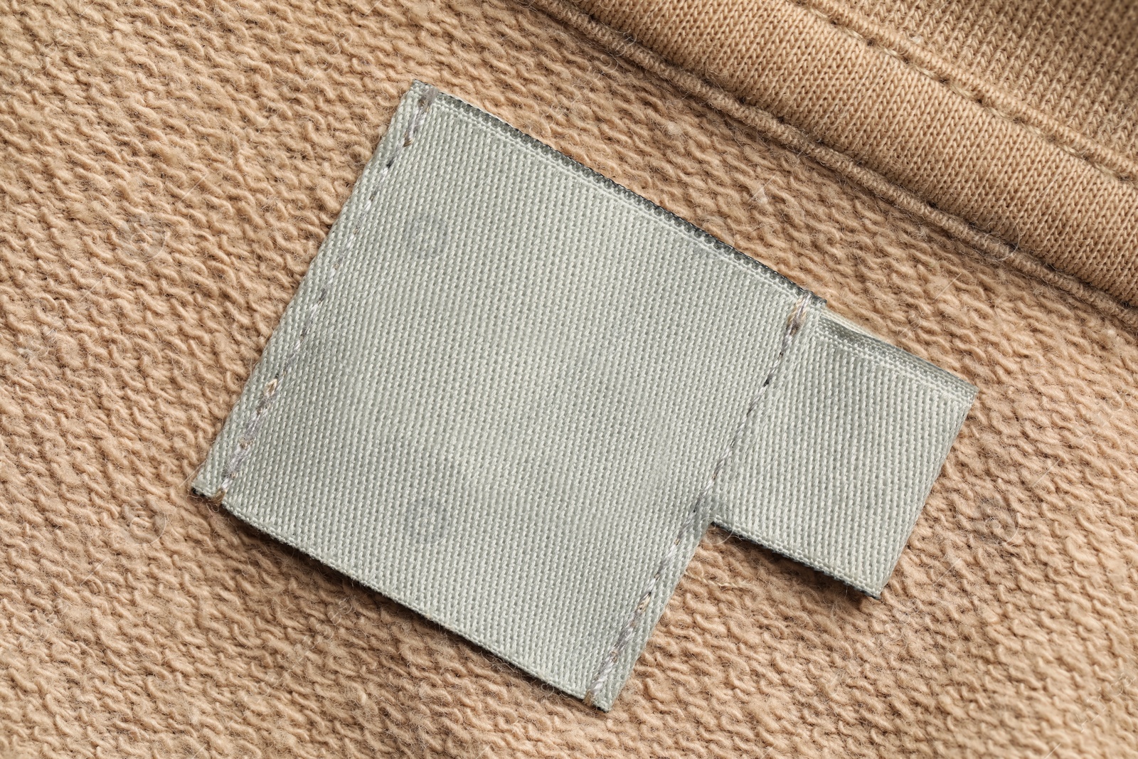 Photo of Clothing label on beige garment, top view
