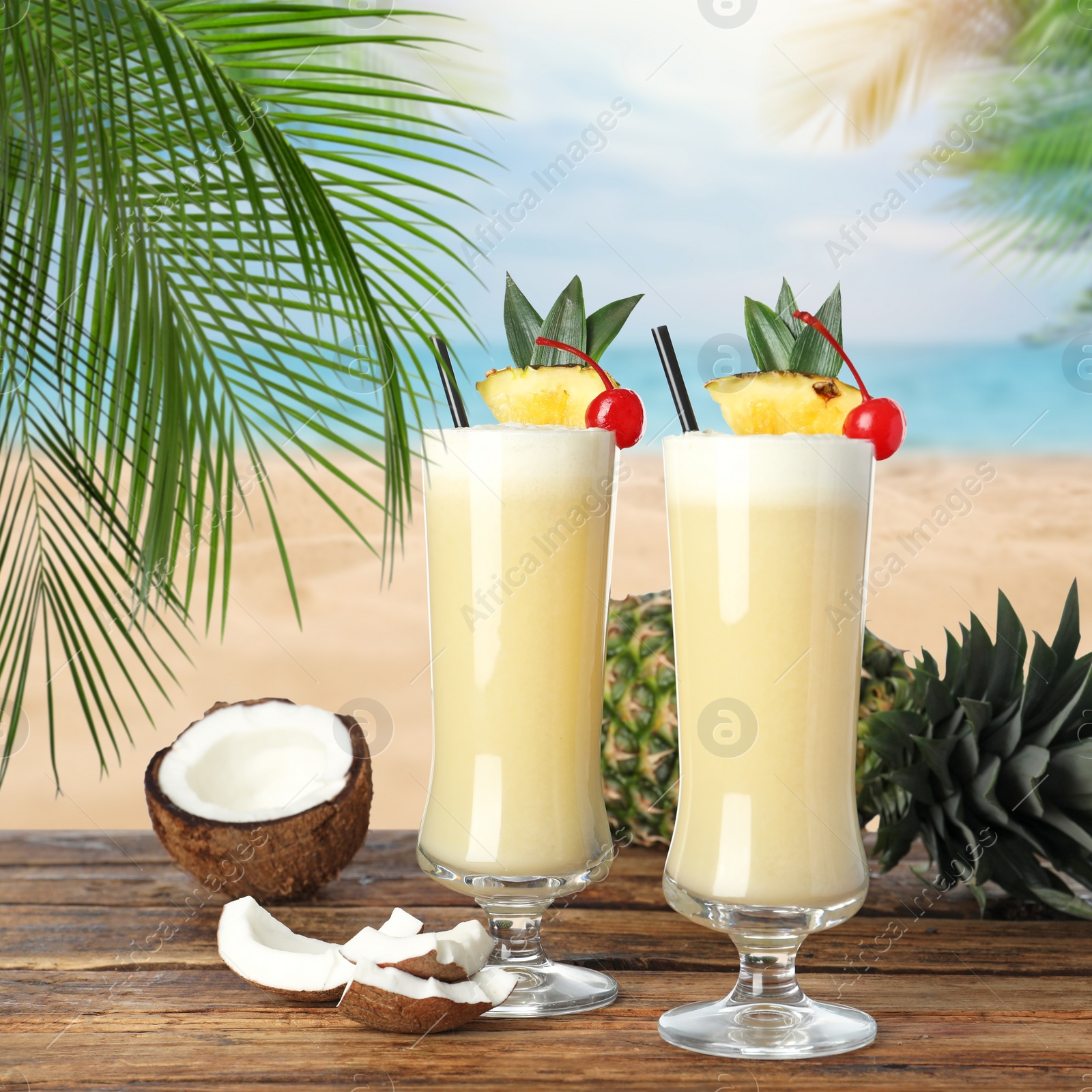 Image of Tasty Pina Colada cocktail on wooden table near ocean 