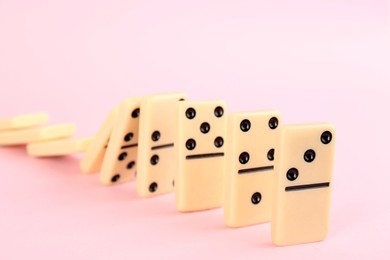 Photo of White domino tiles falling on pink background