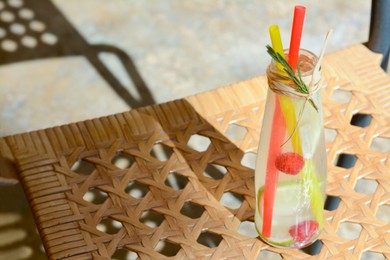 Refreshing tasty lemonade served in glass bottle on wicker surface. Space for text