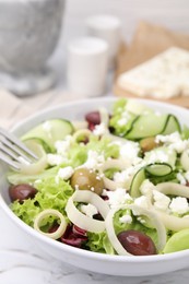 Bowl of tasty salad with leek, olives and cheese on white marble table, closeup