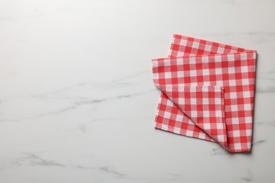 Photo of Red checkered tablecloth on white marble table, top view. Space for text