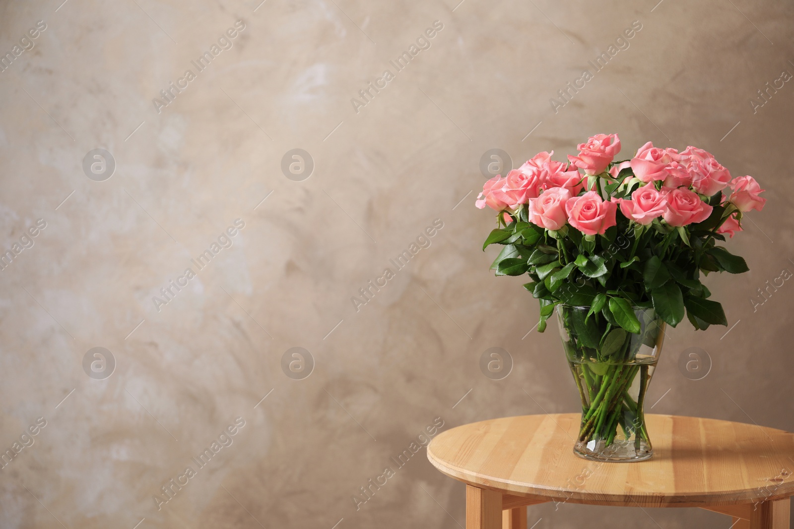 Photo of Vase with beautiful rose flowers on table