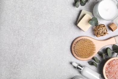 Flat lay composition with spa products and eucalyptus branches on light grey table. Space for text