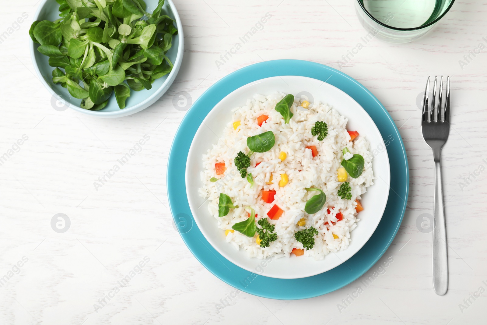 Photo of Boiled rice with vegetables served on wooden table, flat lay