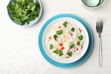 Photo of Boiled rice with vegetables served on wooden table, flat lay