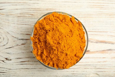 Aromatic saffron powder in bowl on white wooden table, top view