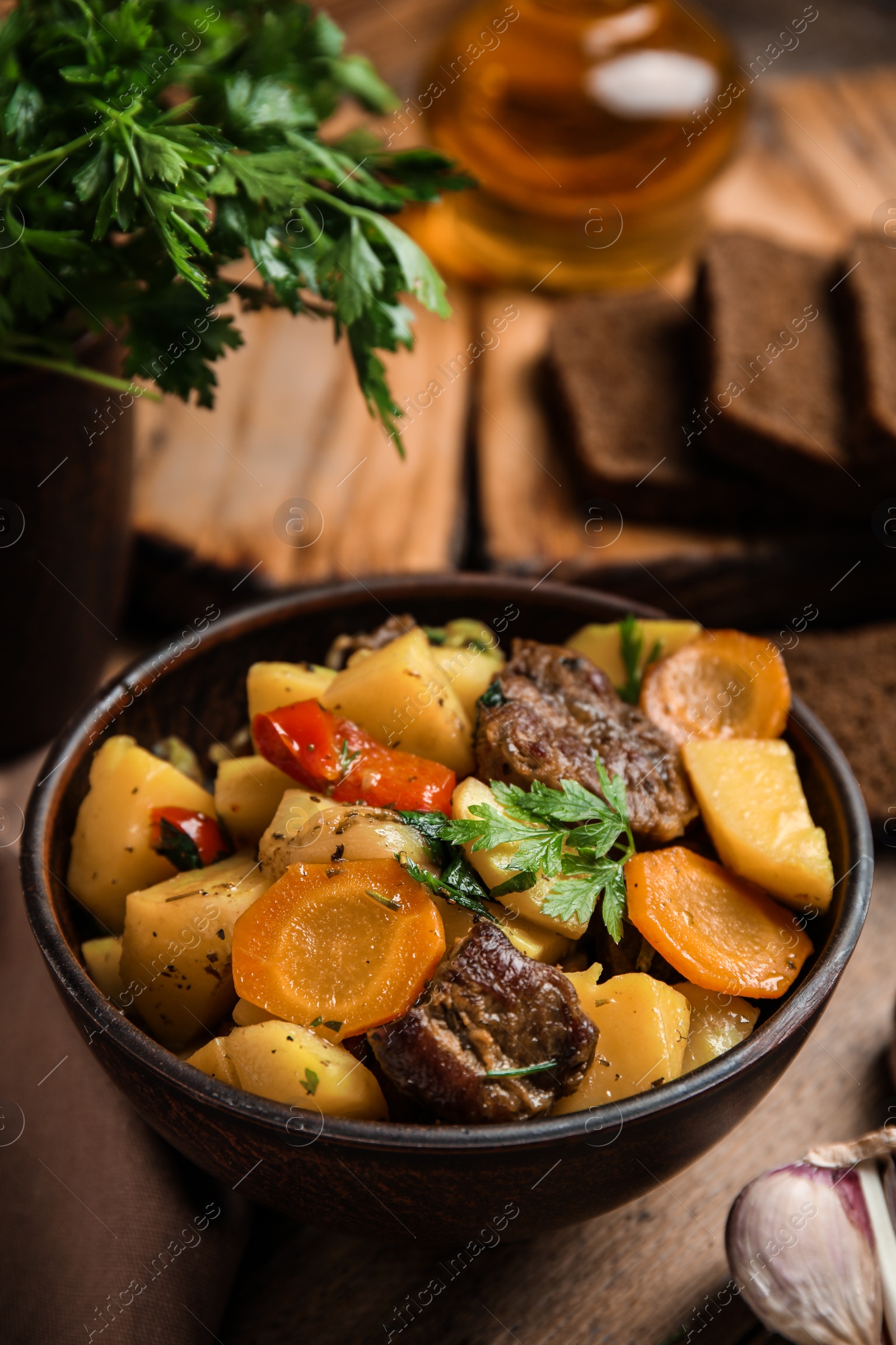 Photo of Tasty cooked dish with potatoes in earthenware on wooden table, closeup