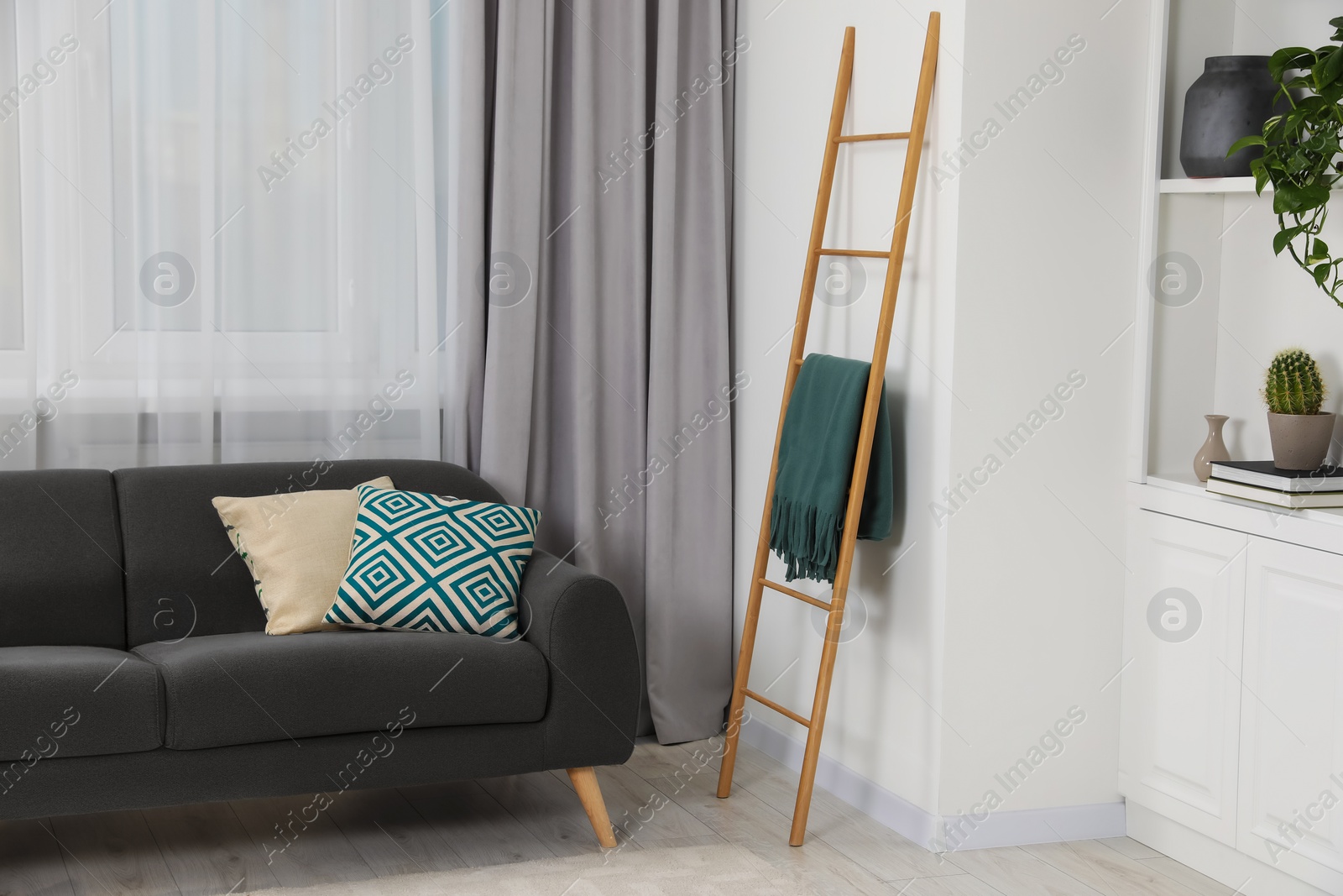 Photo of Wooden ladder near shelving unit and sofa in room