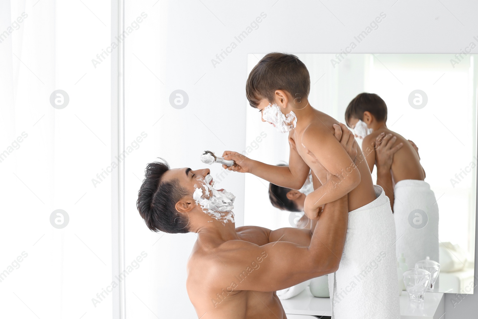 Photo of Father and son having fun while shaving in bathroom