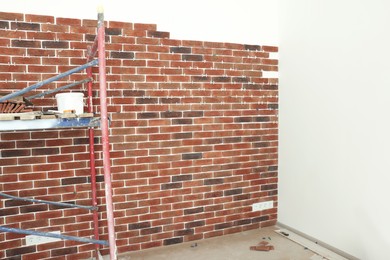 Photo of Scaffolding near wall with decorative bricks and tile leveling system in room