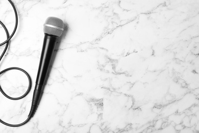 Modern microphone on marble background, top view with space for text