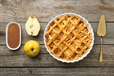 Photo of Tasty homemade quince pie, ingredients and cake server on wooden table, flat lay