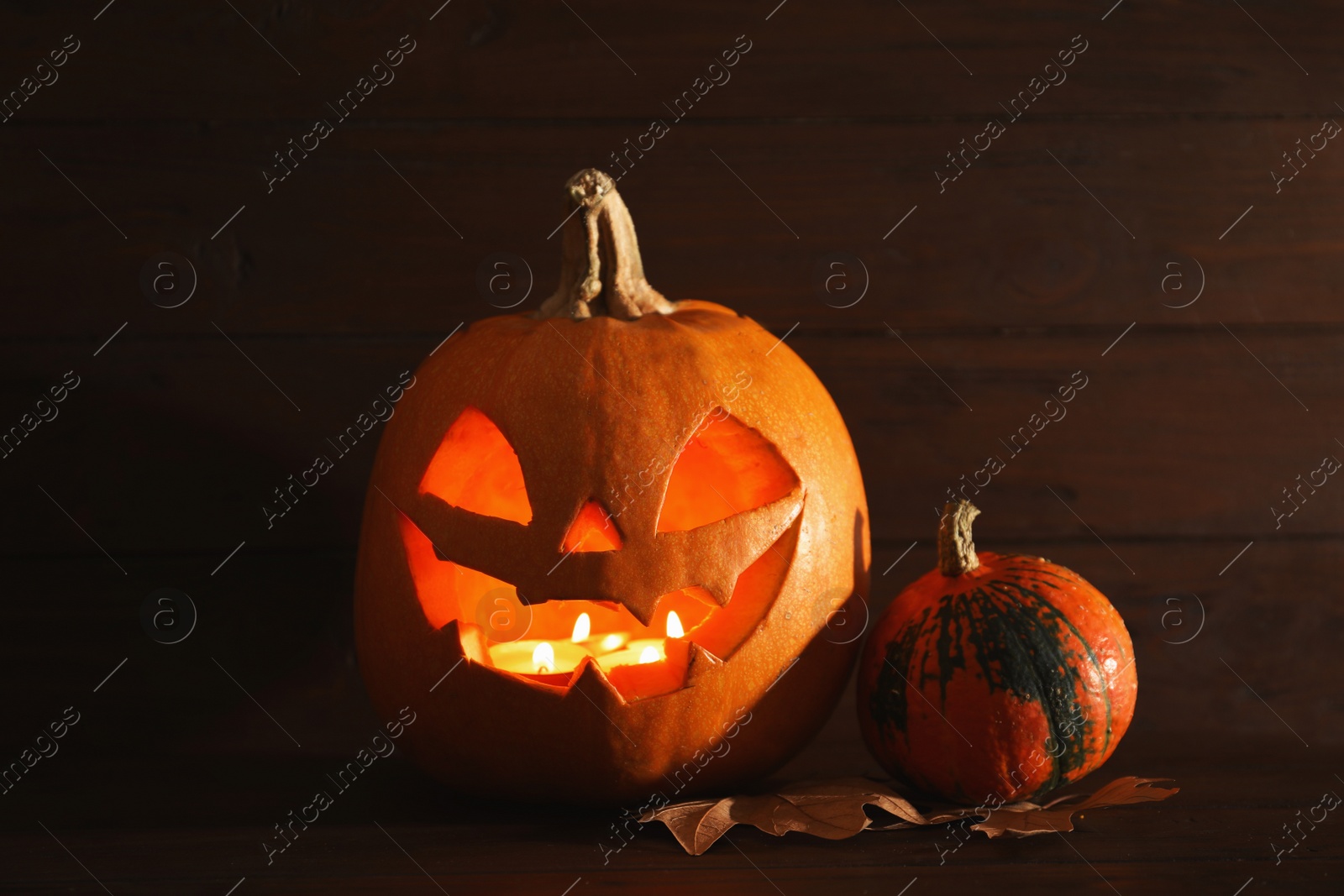 Photo of Halloween pumpkin head jack lantern on table against wooden background