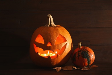 Photo of Halloween pumpkin head jack lantern on table against wooden background