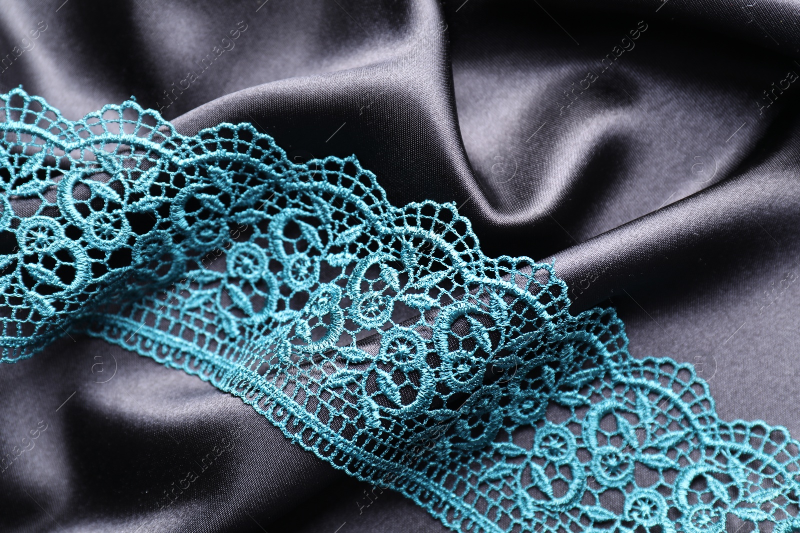 Photo of Beautiful green lace on black fabric, top view