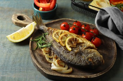 Photo of Delicious dorado fish with vegetables served on wooden table