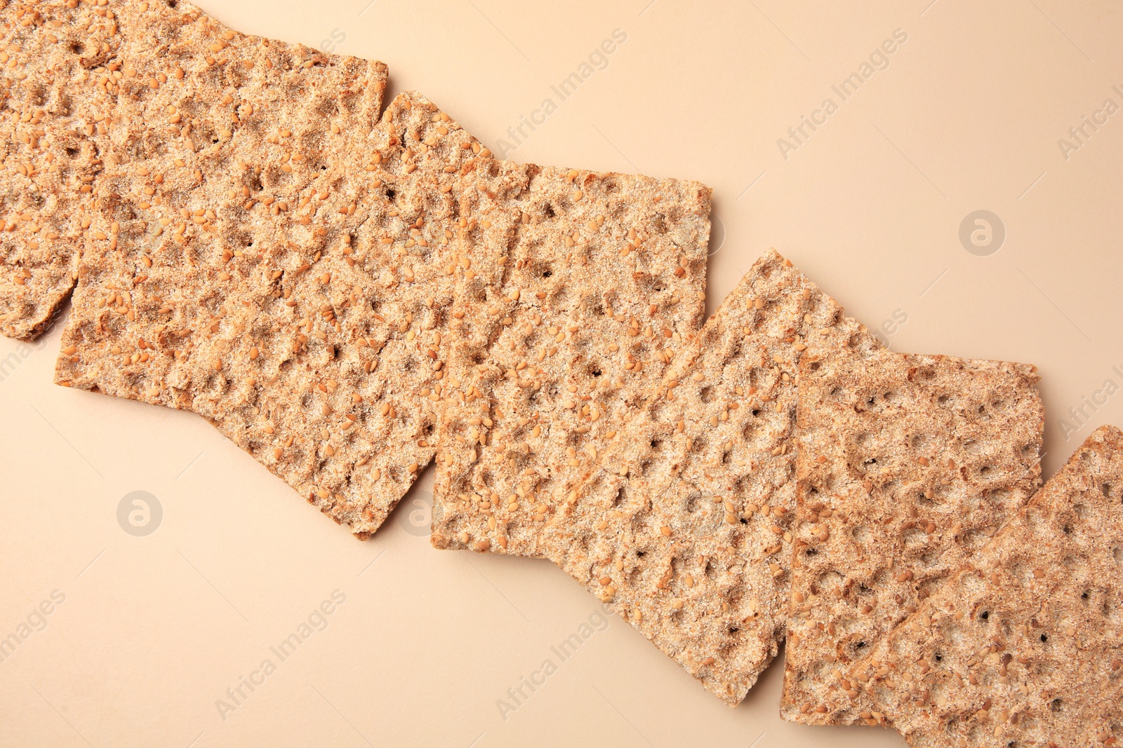 Photo of Fresh crunchy crispbreads on beige background, flat lay