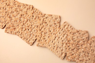 Fresh crunchy crispbreads on beige background, flat lay