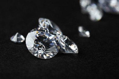 Photo of Many beautiful shiny diamonds on black background, closeup