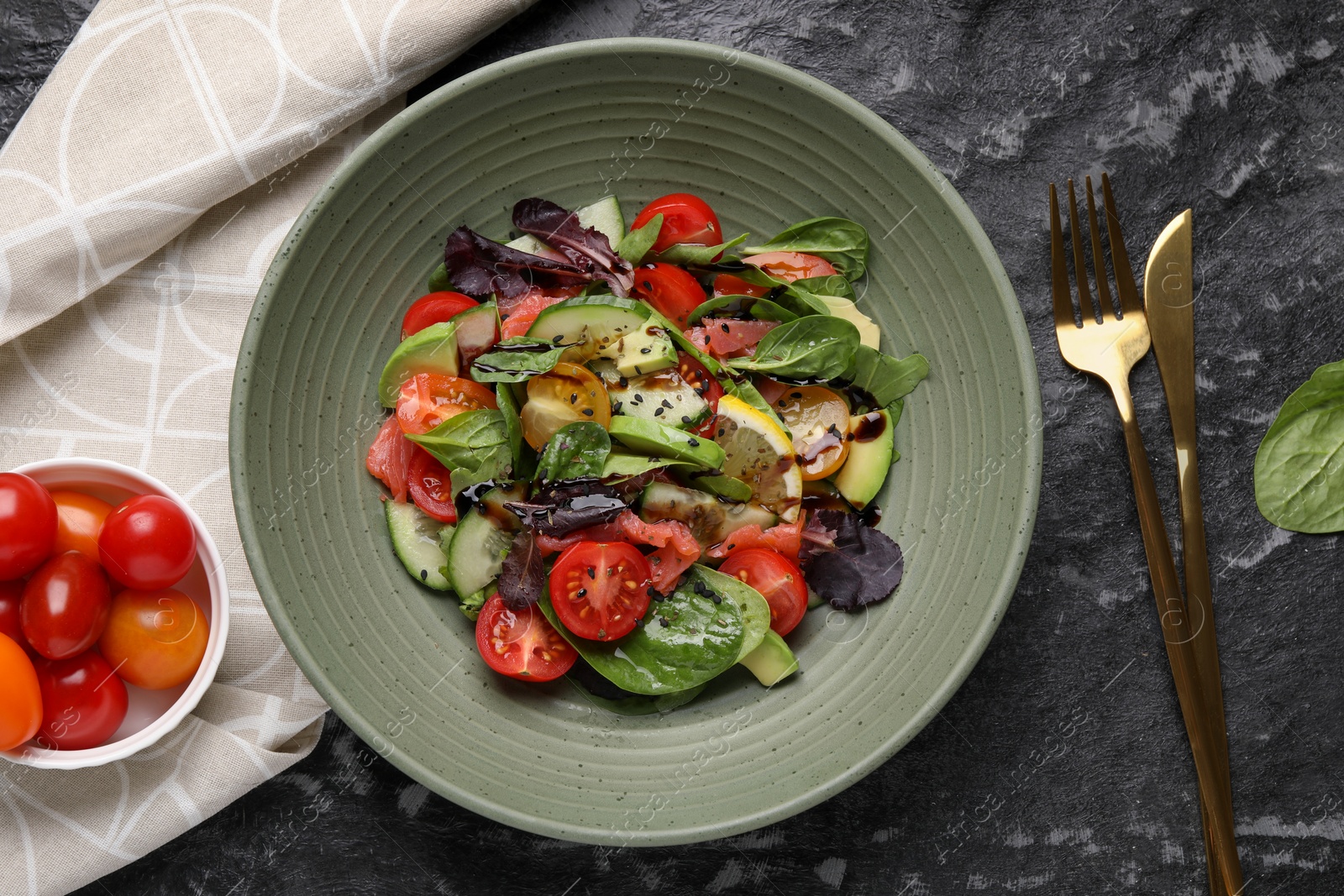 Photo of Delicious vegetable salad served on black textured table, flat lay