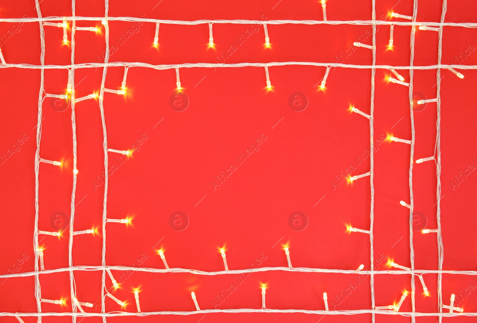 Photo of Glowing Christmas lights on color background, top view