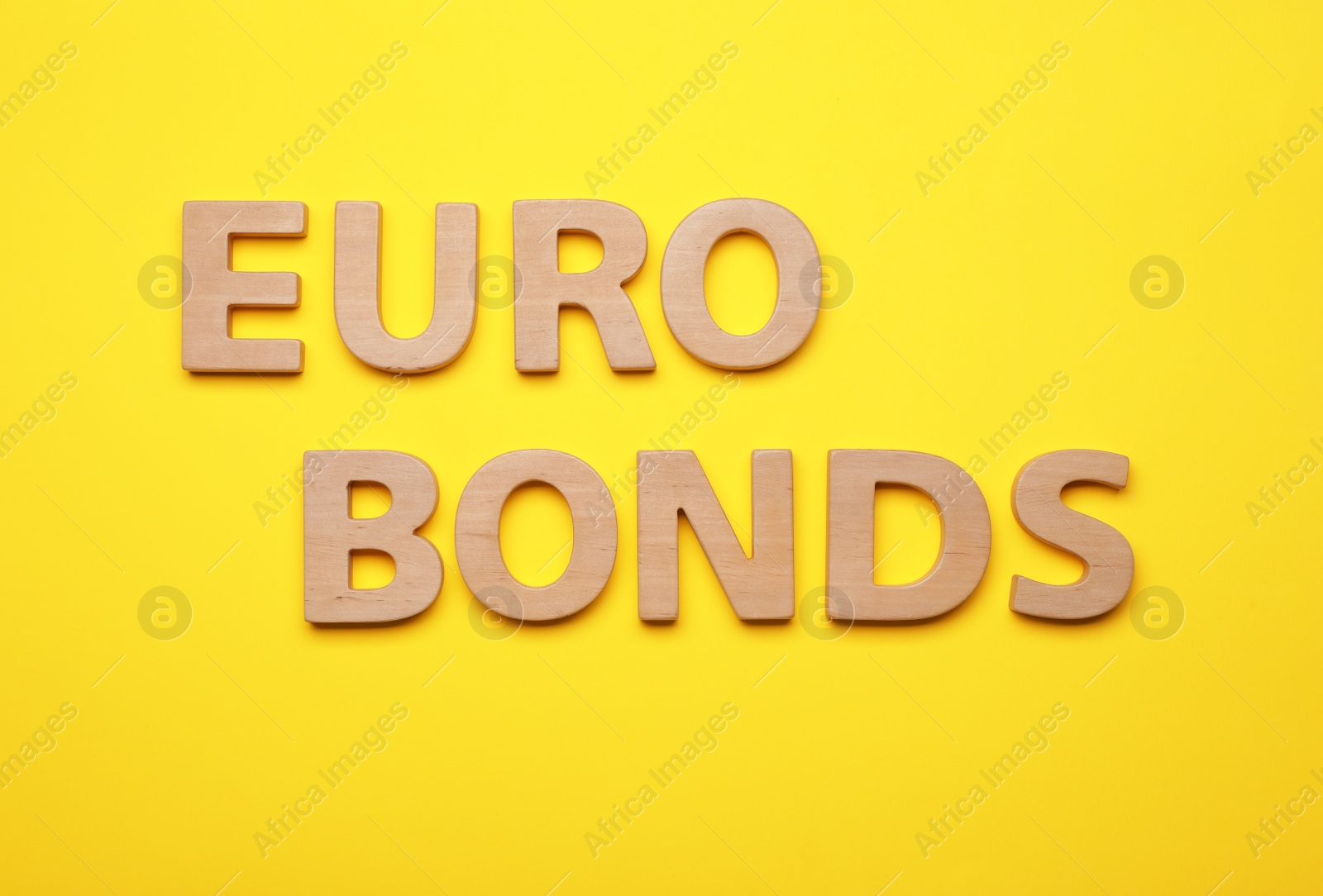 Photo of Word Eurobonds made of wooden letters on yellow background, flat lay