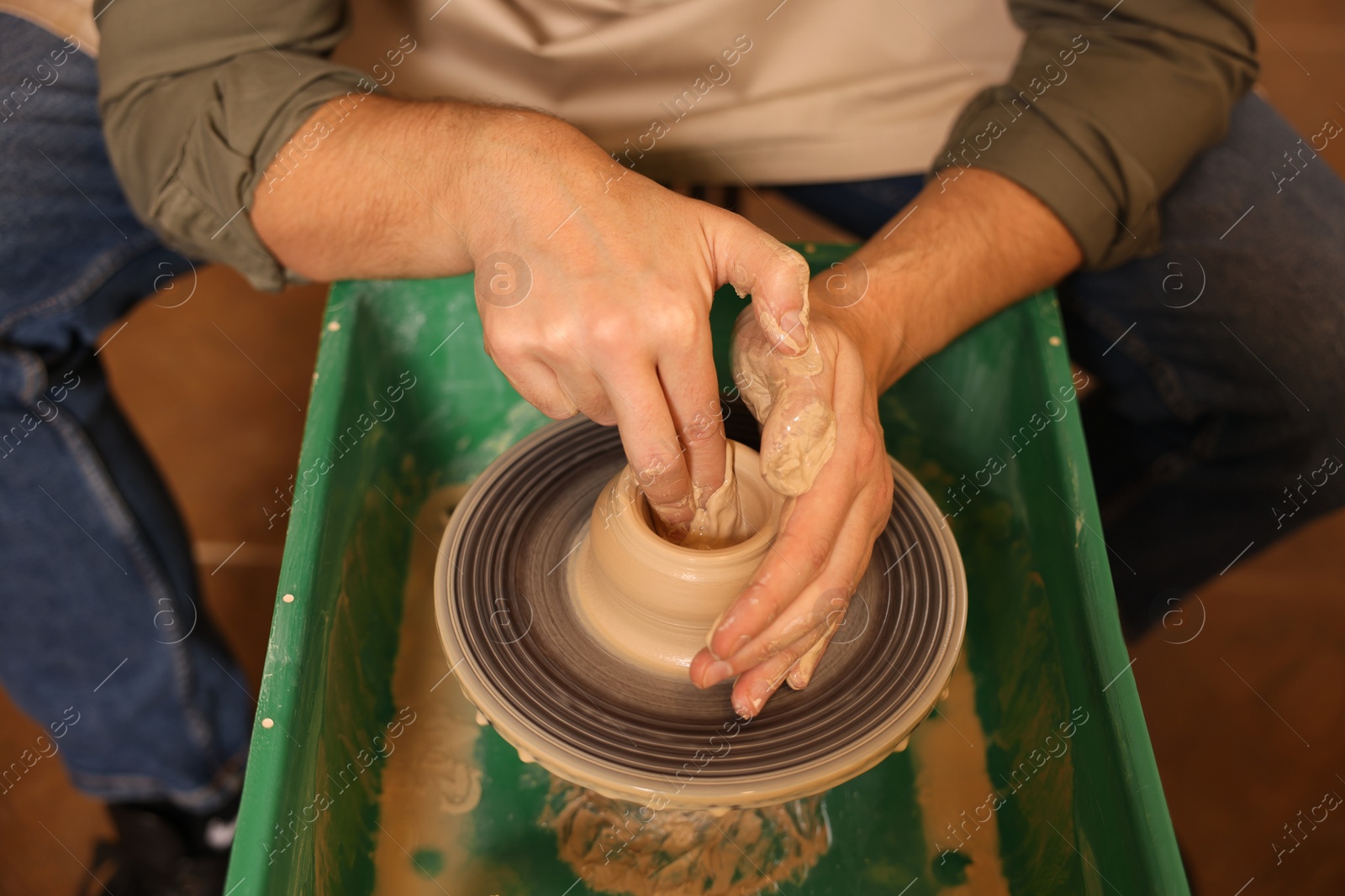 Photo of Clay crafting. Man making bowl on potter's wheel, closeup