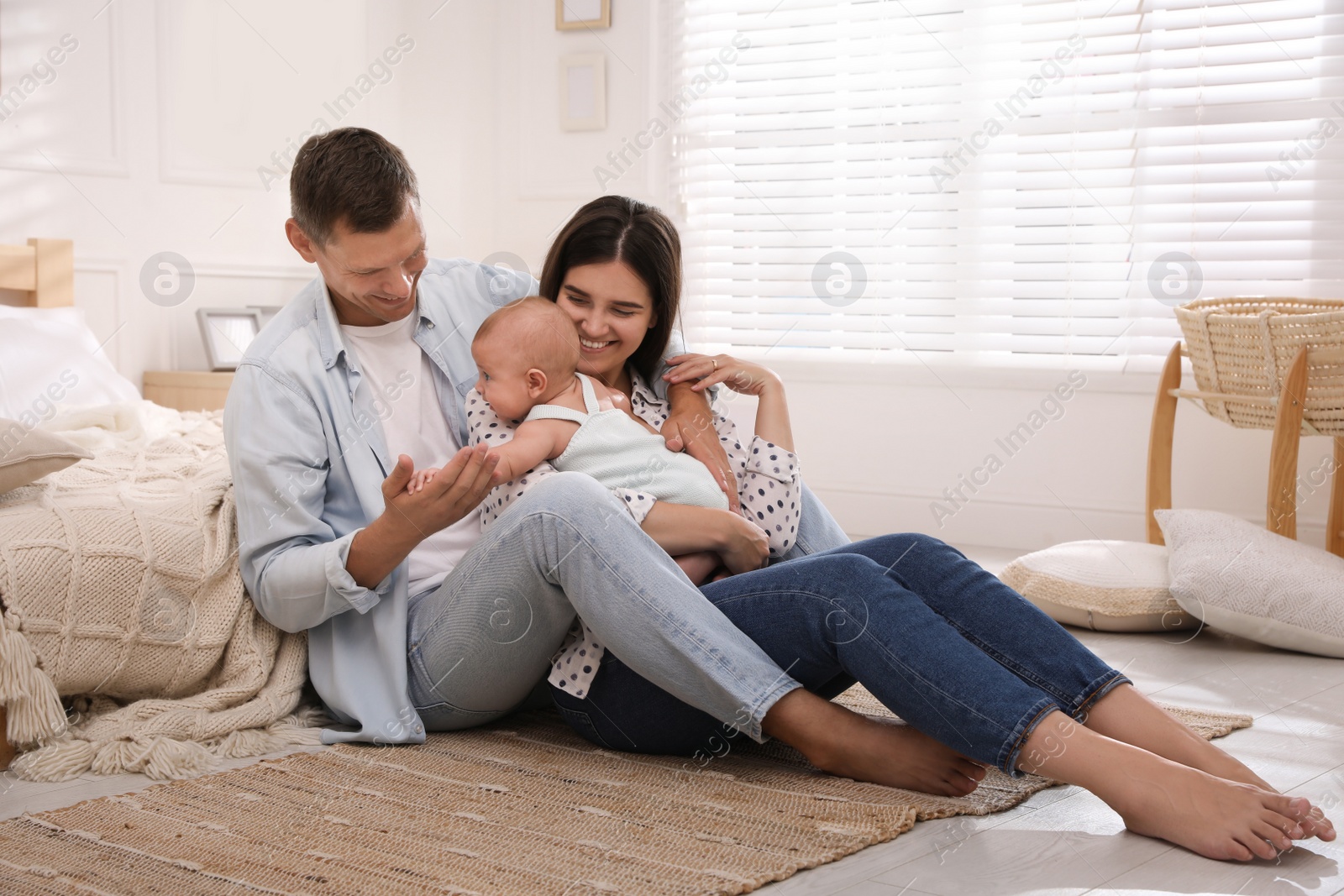 Photo of Happy family with their cute baby on floor in bedroom