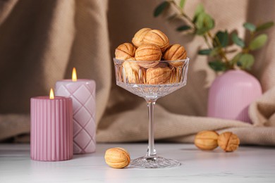 Photo of Delicious nut shaped cookies and burning candles on white table