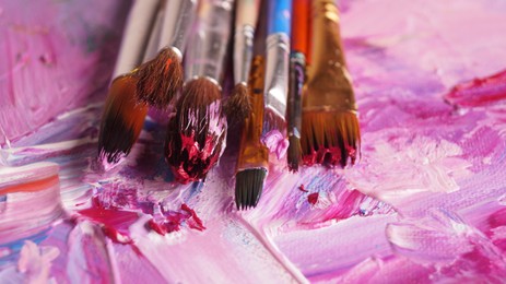 Brushes on canvas with mixed bright paints, closeup