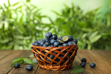 Tasty ripe blueberries in wicker bowl on wooden table