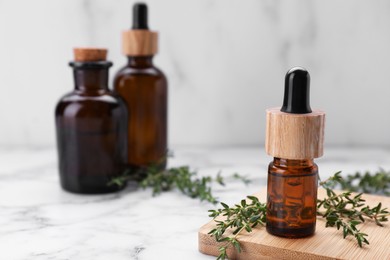 Photo of Thyme essential oil on white marble table, space for text