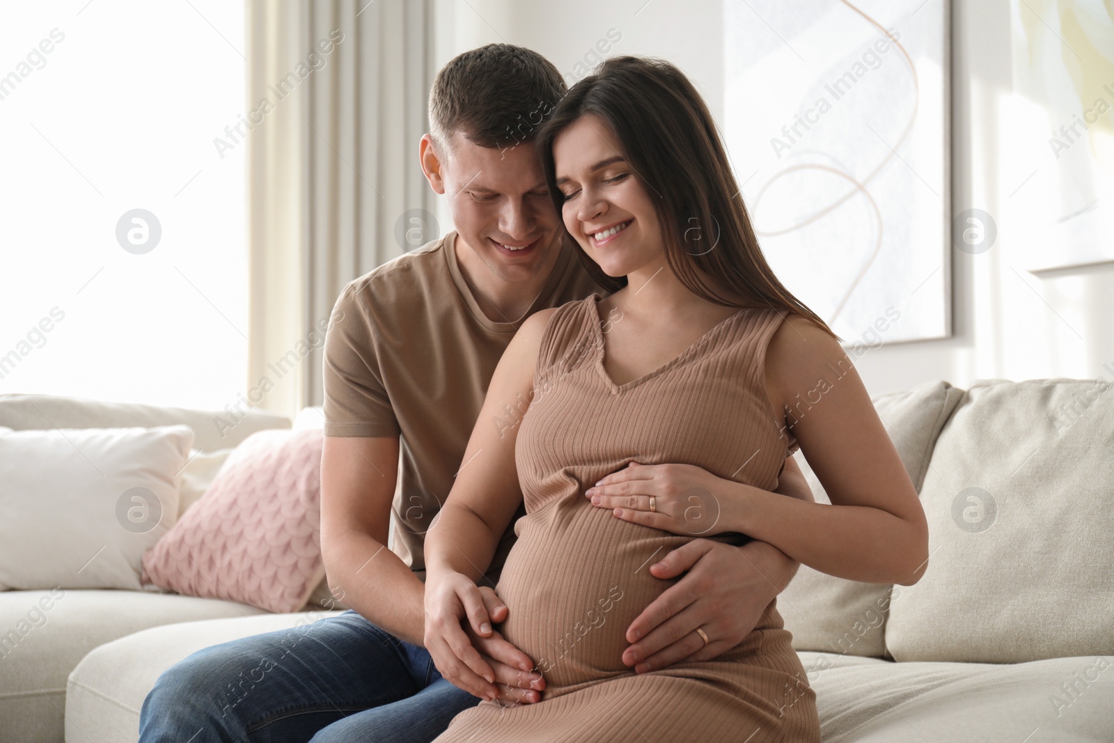 Photo of Man touching his pregnant wife's belly at home