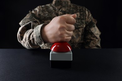Photo of Serviceman pressing red button of nuclear weapon at black table, closeup. War concept