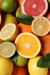 Photo of Different fresh citrus fruits and leaves as background, above view