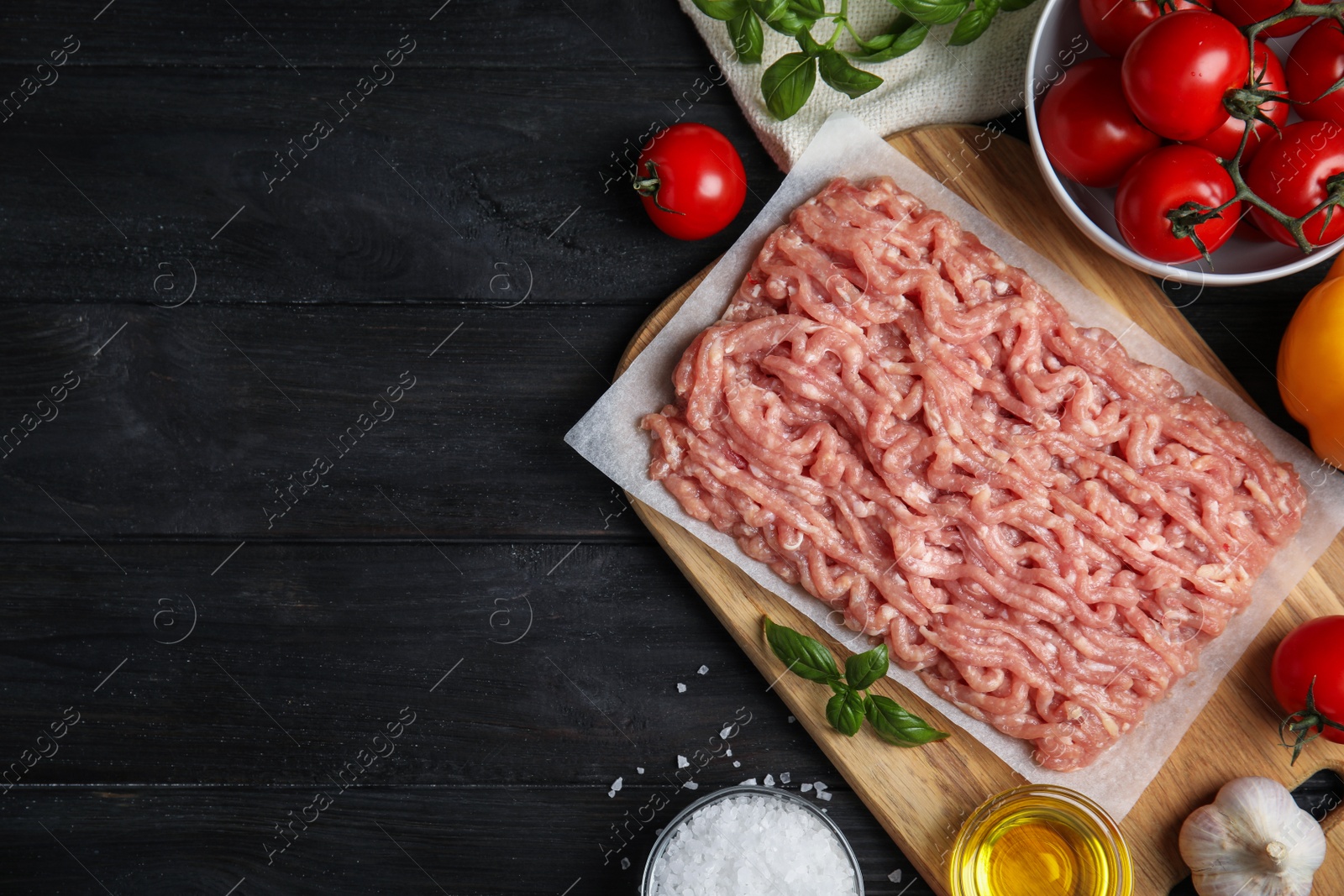 Photo of Raw chicken minced meat and ingredients on black wooden table, flat lay. Space for text