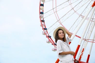 Beautiful young woman near Ferris wheel outdoors, low angle view