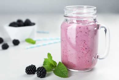 Photo of Mason jar with blackberry yogurt smoothie on table