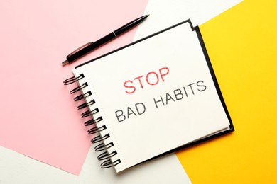 Notebook with phrase Stop Bad Habits and pen on color background, flat lay