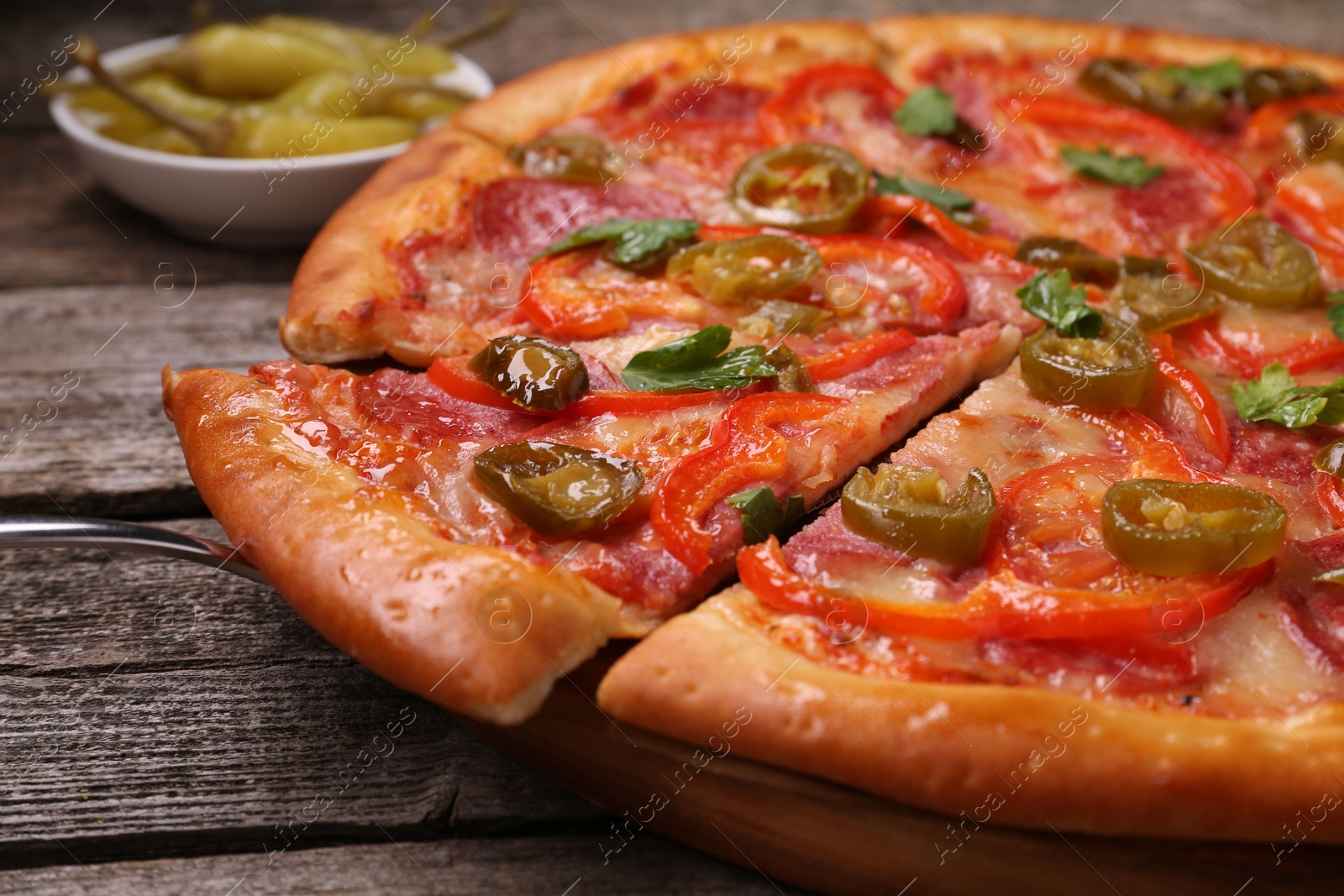 Photo of Delicious pizza Diablo and pickled peppers on wooden table, closeup