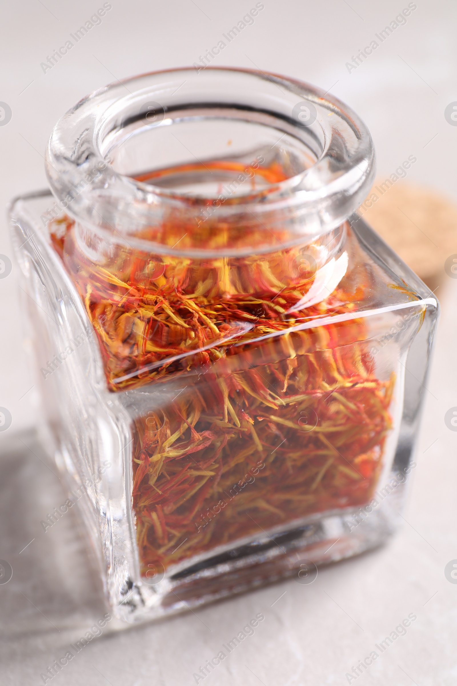 Photo of Aromatic saffron and glass jar on light gray table, closeup