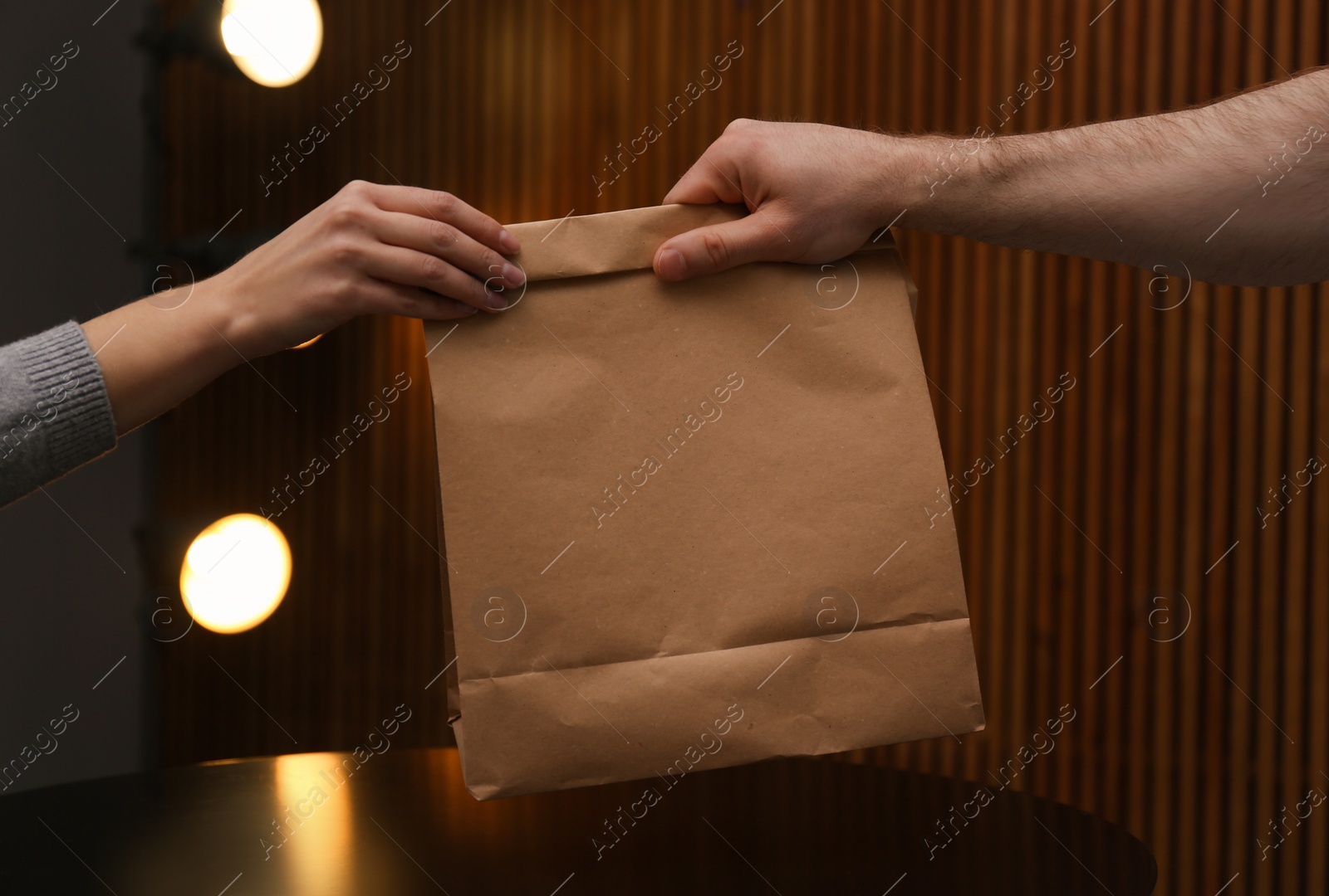 Photo of Man giving paper bag with order to customer in cafe, closeup. Mock up for design