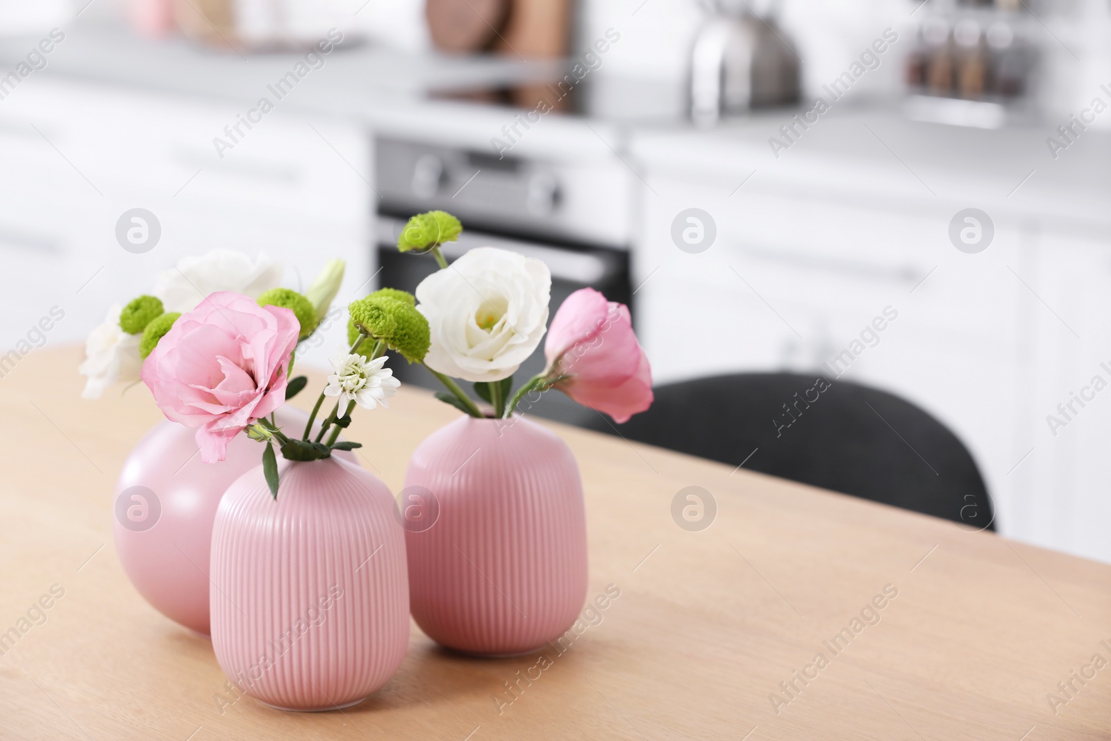 Photo of Vases with beautiful flowers on table in kitchen interior. Space for text