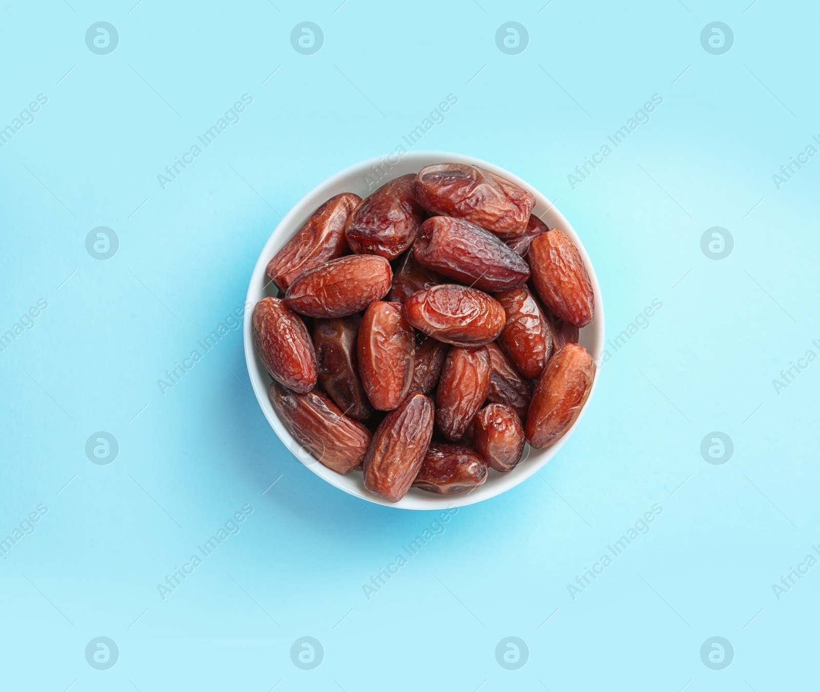 Photo of Bowl with sweet dried date fruits on color background, top view