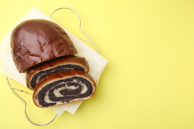 Photo of Slices of poppy seed roll on yellow background, top view with space for text. Tasty cake