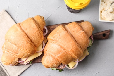Photo of Tasty croissant sandwiches with salami on grey background