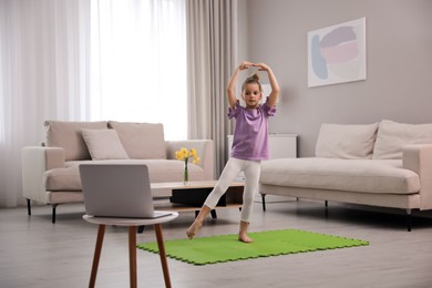 Cute little girl taking online dance class at home